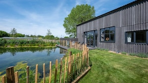 A modern building with large windows, a pond, and a well-maintained lawn. - 5 Bed in Briston (oc-2305) (Briston)