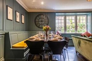 A dining room with a long table set for a meal, framed botanical prints on the wall, and a large clock. - 5 Bed in Padstow (oc-p00595) (Padstow)