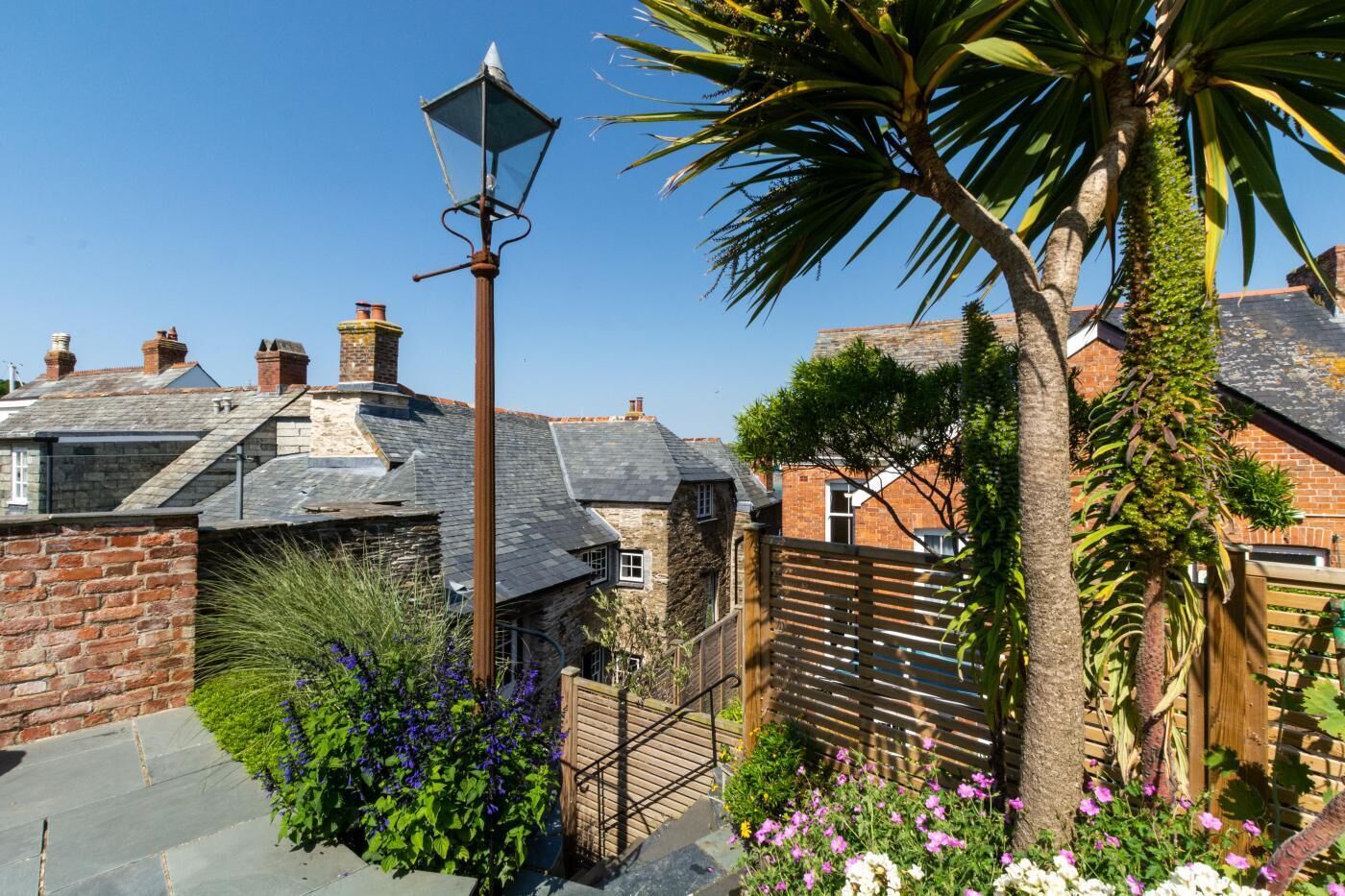 A traditional stone house with a sloped roof, a wooden fence, and a street lamp.