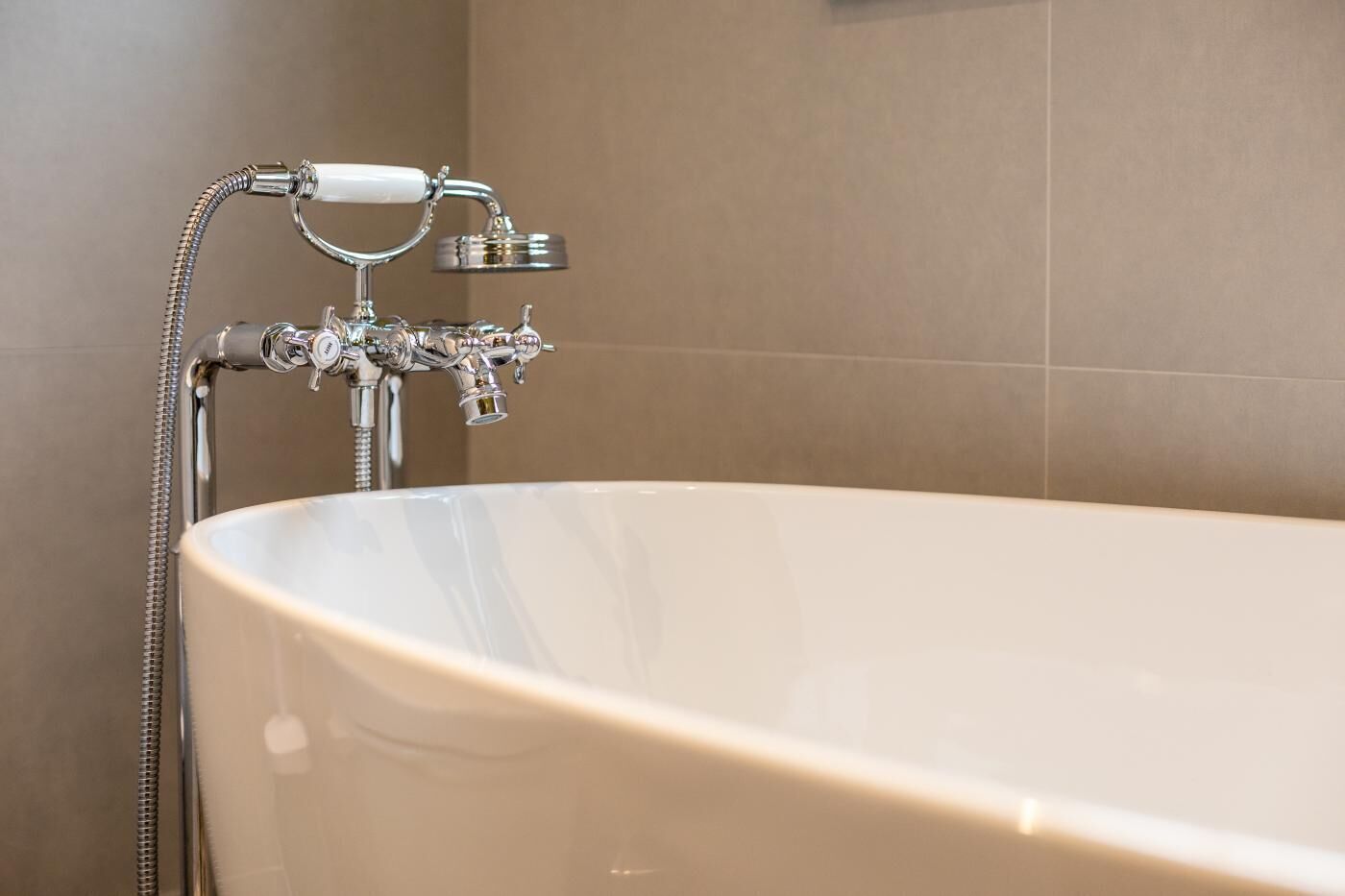 A bathtub with a shower attachment, a faucet, and a hose.