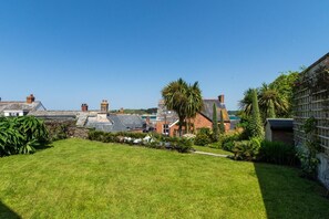 A residential area with houses, a grassy lawn, and various plants. - 5 Bed in Padstow (oc-p00595) (Padstow)