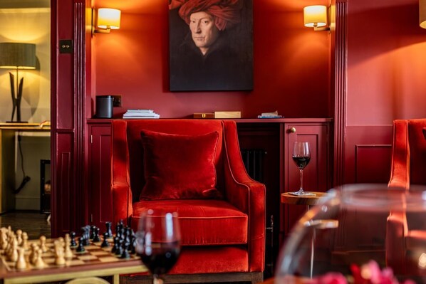 A red velvet armchair, a chessboard, and a wine glass in a warmly lit room with a painting on the wall. - 5 Bed in Padstow (oc-p00595) (Padstow)