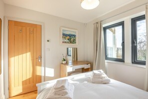 A bedroom with a bed, a wooden door, a desk, a window, and a painting on the wall. - 3 Bed in North Sunderland (oc-t33656) (North Sunderland)
