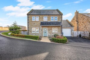 A two-story stone house with a garage, a driveway, and a well-maintained lawn. - 3 Bed in North Sunderland (oc-t33656) (North Sunderland)