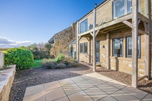 A stone building with a covered patio and a gravel driveway. - 3 Bed in North Sunderland (oc-t33656) (North Sunderland)