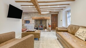 A cozy living room with a stone fireplace, leather sofas, and a flat-screen TV mounted on the wall. - 4 Bed in Peterchurch (oc-s34019) (Peterchurch)