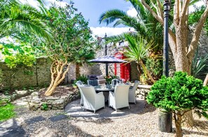 An outdoor patio with wicker furniture, a red telephone booth, and a stone wall. - 4 Bed in Tenby (oc-pw9264) (Tenby)