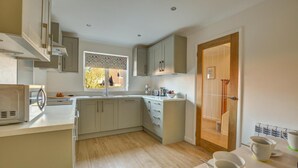 Una cocina moderna con armarios de madera clara, microondas integrado y ventana con vistas al exterior.