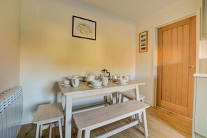 A small, cozy room with a white table set for tea, a radiator, and a wooden door.