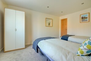 A bedroom with a wardrobe, two beds, a mirror, and a door. - 3 Bed in Langham (oc-1828) (Langham)