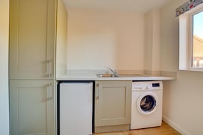 A compact kitchen with a built-in washing machine and a small refrigerator.