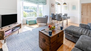Una sala moderna con televisor, sofá, mesa de centro y comedor.
