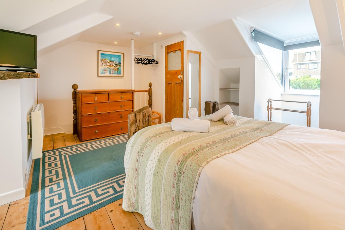 Un dormitorio con cama, cómoda y vistas al exterior.