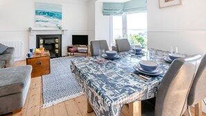 Una sala de estar moderna con comedor, chimenea y ventanas amplias.