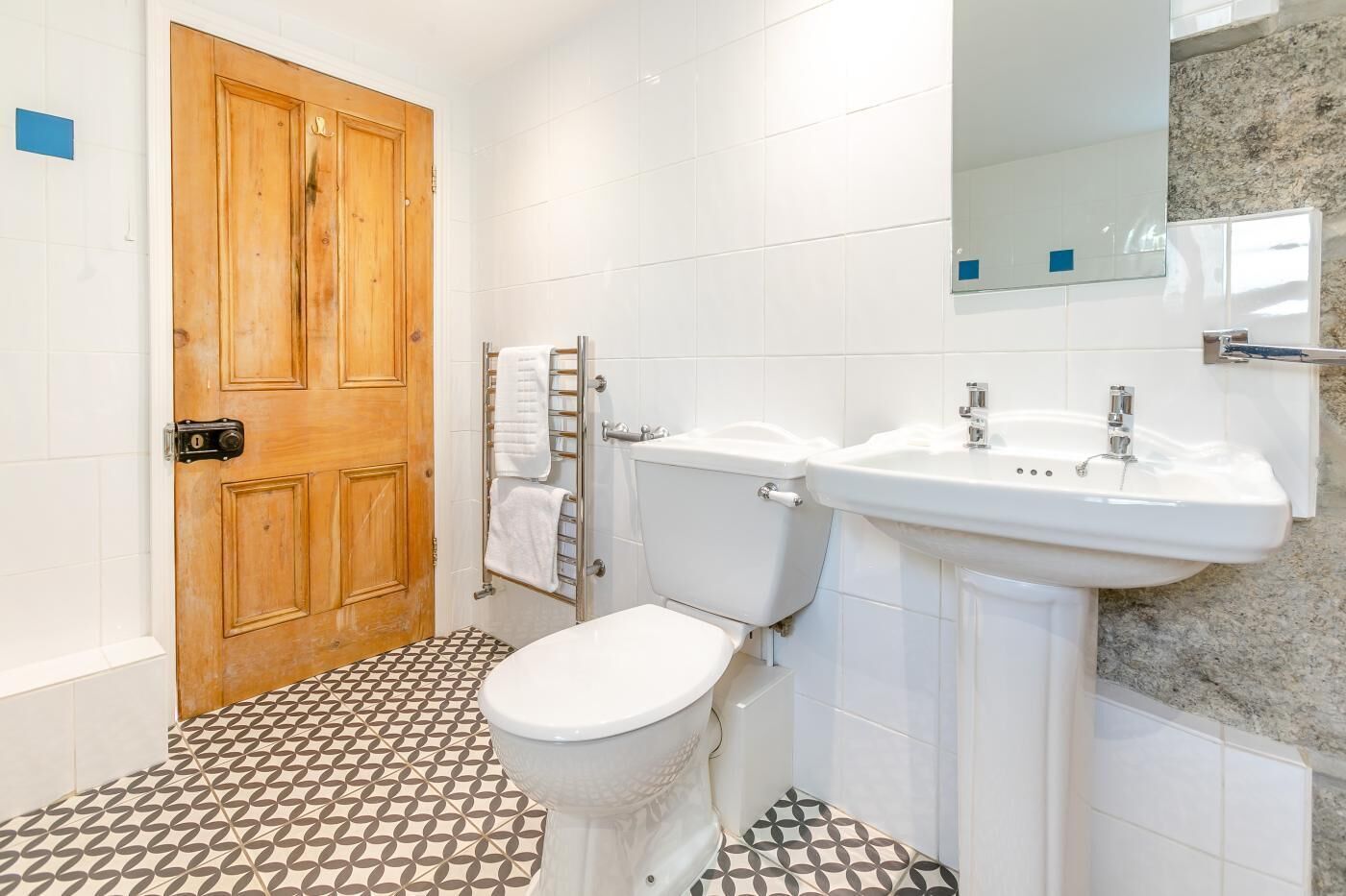 A bathroom with a wooden door, a toilet, a sink, and a towel rack.