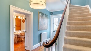 Un escalier avec une rampe en bois mène à un espace repas où une table est dressée pour le repas.