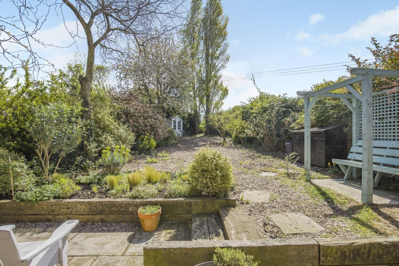 A garden with a wooden bench, a small pond, and a white gazebo.
