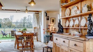 Una cocina rústica con armarios de madera, un comedor con mesa y sillas, y vistas al exterior.