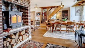 Una sala de estar acogedora con chimenea de ladrillo, escalera de madera y comedor con mesa y sillas.