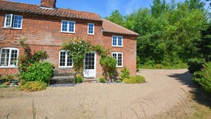A two-story brick house with a tiled roof, a front garden with a bench, and a gravel driveway. - 2 Bed in Little Barningham (oc-1817) (Little Barningham)