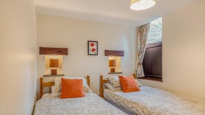 A twin room with two beds, each with a wooden headboard, a nightstand, a lamp, and a floral-patterned bedspread. - 2 Bed in Earl Sterndale (oc-p33566) (Earl Sterndale)