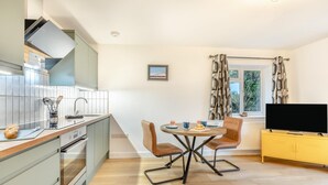 Una cocina moderna con comedor, televisión de pantalla plana y ventana con cortinas.