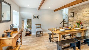 Un'ampia cucina con un tavolo da pranzo in legno apparecchiato, una parete in pietra e una scala che conduce al piano superiore.