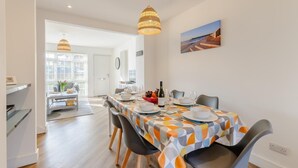 Comedor con una mesa lista para cuatro, una botella de vino y un cuadro en la pared.