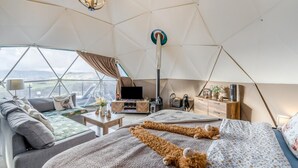 Une chambre confortable aménagée comme une tente, avec un canapé, un lit, une télévision et un radiateur.