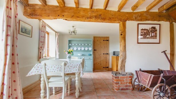 A rustic dining room with a wooden ceiling, a table set for two, and a vintage cart. - 2 Bed in Erpingham (oc-2278) (Erpingham)