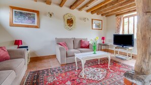 A cozy living room with a sofa, a coffee table, a TV, and a large window. - 2 Bed in Erpingham (oc-2278) (Erpingham)