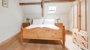 A wooden bed in a room with a sloped ceiling, wooden wardrobe, and a small window. - 2 Bed in Erpingham (oc-2278) (Erpingham)
