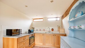 A compact kitchen with wooden cabinets, a built-in oven, a microwave, and a sink. - 2 Bed in Erpingham (oc-2278) (Erpingham)