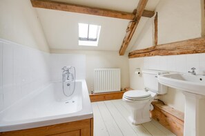 A bathroom with a bathtub, toilet, and sink, featuring wooden beams and white tiles. - 2 Bed in Erpingham (oc-2278) (Erpingham)