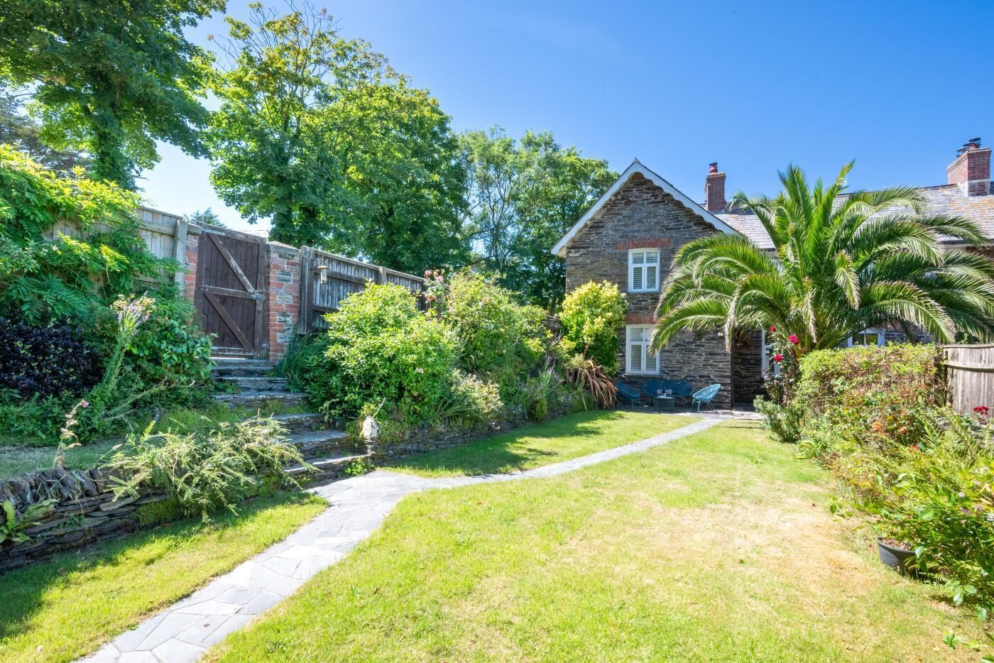Une maison en pierre avec un chemin de pierre menant à un patio.