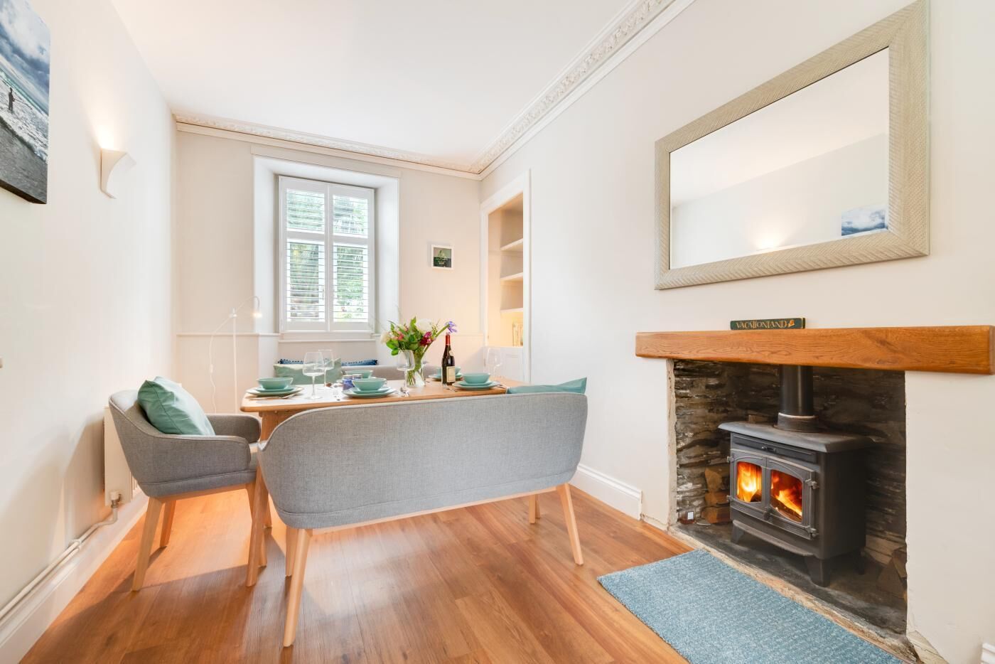 Een eetgedeelte met een tafel gedekt voor twee personen, een open haard en een grote spiegel erboven.