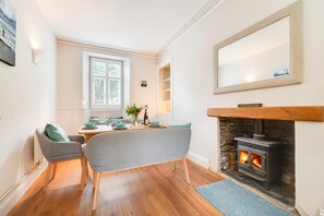 A dining area with a table set for two, a fireplace, and a large mirror above it. - 3 Bed in Boscastle (oc-tchest) (Boscastle)