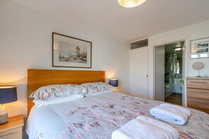 A neatly made bed with floral bedding, a bedside lamp, and a framed picture above it. - 3 Bed in Saundersfoot (oc-pw9101) (Saundersfoot)