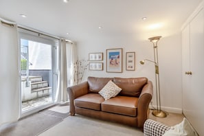 Ein Wohnzimmer mit einer braunen Ledersofa, einer Stehlampe und gerahmten Bildern an der Wand.