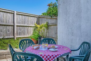 A patio with a checkered tablecloth, outdoor chairs, and a table set with food and drinks. - 3 Bed in Saundersfoot (oc-pw9101) (Saundersfoot)
