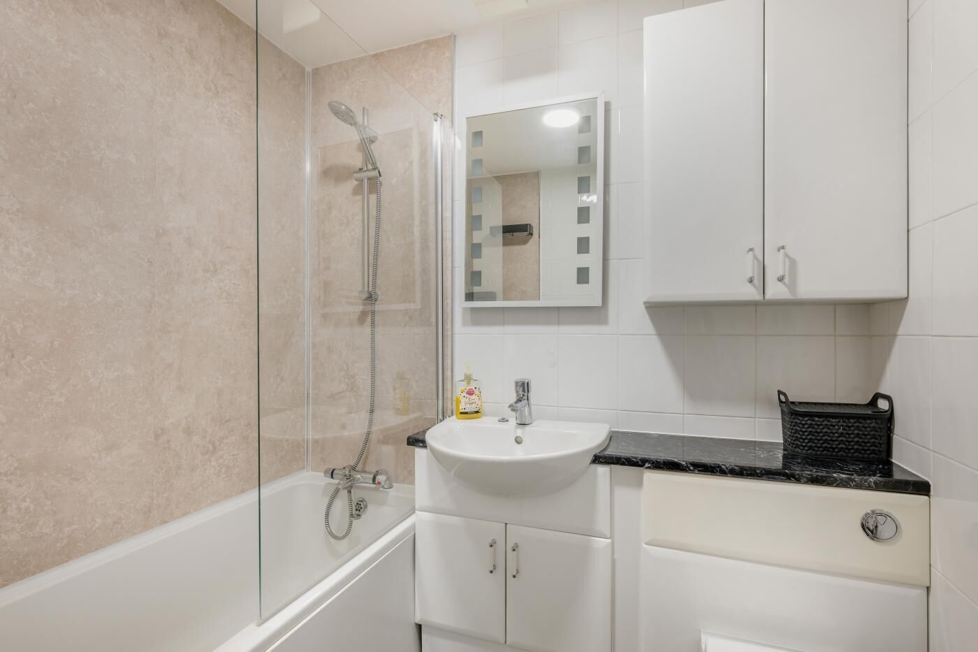 Un baño moderno con ducha envuelta en vidrio, un lavamanos blanco y un espejo encima.
