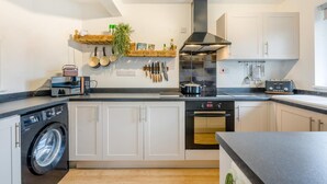 Een moderne keuken met een wasmachine, oven en diverse keukengerei aan de muur.