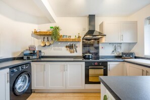 Eine moderne Küche mit Waschmaschine, Backofen und verschiedenen Küchenutensilien an der Wand.