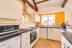 A modern kitchen with white cabinetry, a black countertop, a built-in oven, and a window with a view. - 2 Bed in Milfield (oc-nb1982) (Milfield)