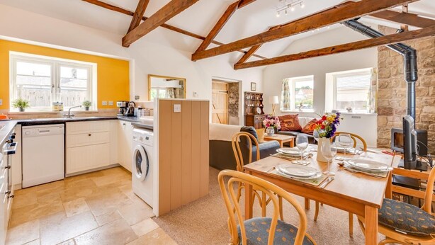 A kitchen with a dishwasher, washing machine, and a dining area with a table set for two. - 2 Bed in Milfield (oc-nb1982) (Milfield)