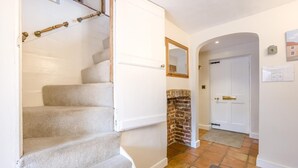 A staircase leading to a landing with a brick wall and a white door. - 3 Bed in Southwold (oc-stan) (Southwold)