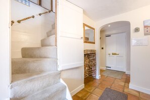 Un escalier menant à un palier avec un mur en briques et une porte blanche.