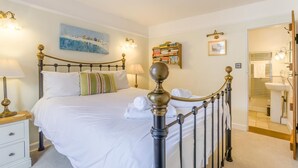 A neatly made bed with white linens, a bedside table with a lamp, and a painting on the wall. - 3 Bed in Southwold (oc-stan) (Southwold)
