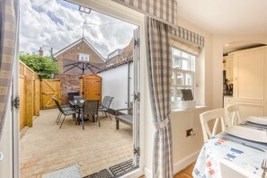 Une terrasse avec une table et des chaises, une clôture en bois et un mur en briques.