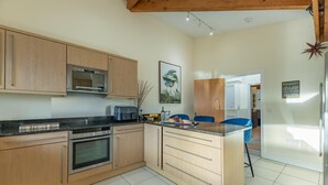 A modern kitchen with wooden cabinets, a built-in oven, a microwave, and a coffee maker.